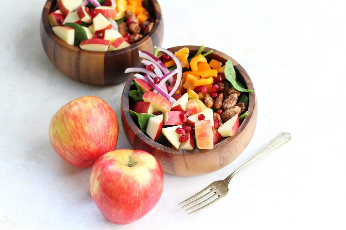 Best Apple Spinach Harvest Salad Salads served in wooden bowls and two sweet apples as sides.