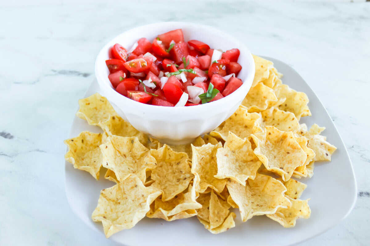 Fresh watermelon salsa with tortilla chips Fresh watermelon salsa with tomatoes, onion, and basil, surrounded by tortilla chips.