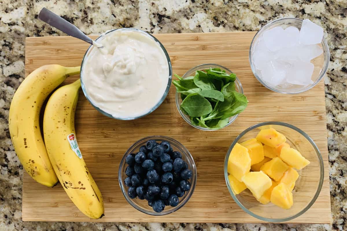 Banana, Blueberry, and Mango Smoothie ingredients are displayed on a chopping board.