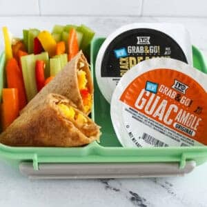 Healthy breakfast for kids with egg and veggie taquitos, colorful bell pepper sticks, and ¡Yo Quiero! Grab & Go guacamole and bean dip cups in a lunchbox